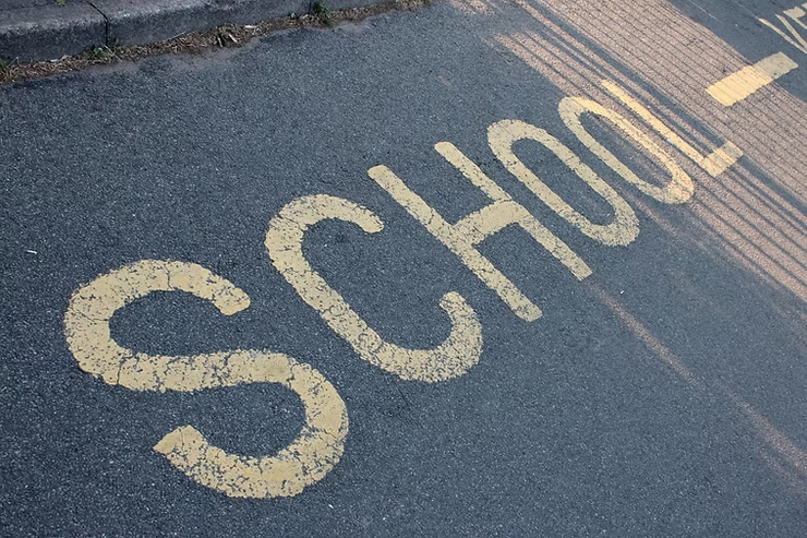 Yellow road marking "School" UK painted on an asphalt road