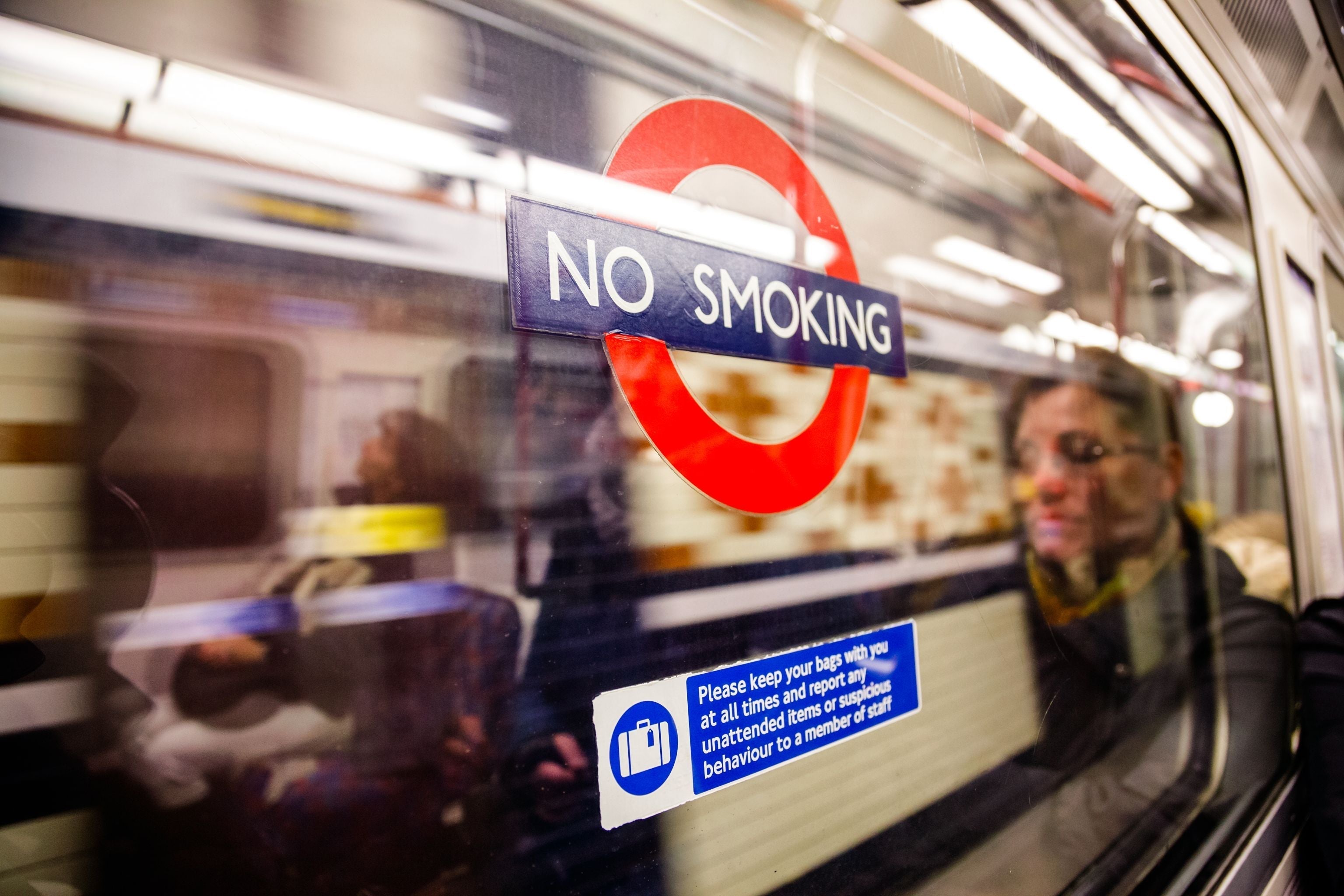 LONDON, UK - NOVEMBER 03, 2012: passengers reflecting in a London Underground carriage window with No Smoking sign on it